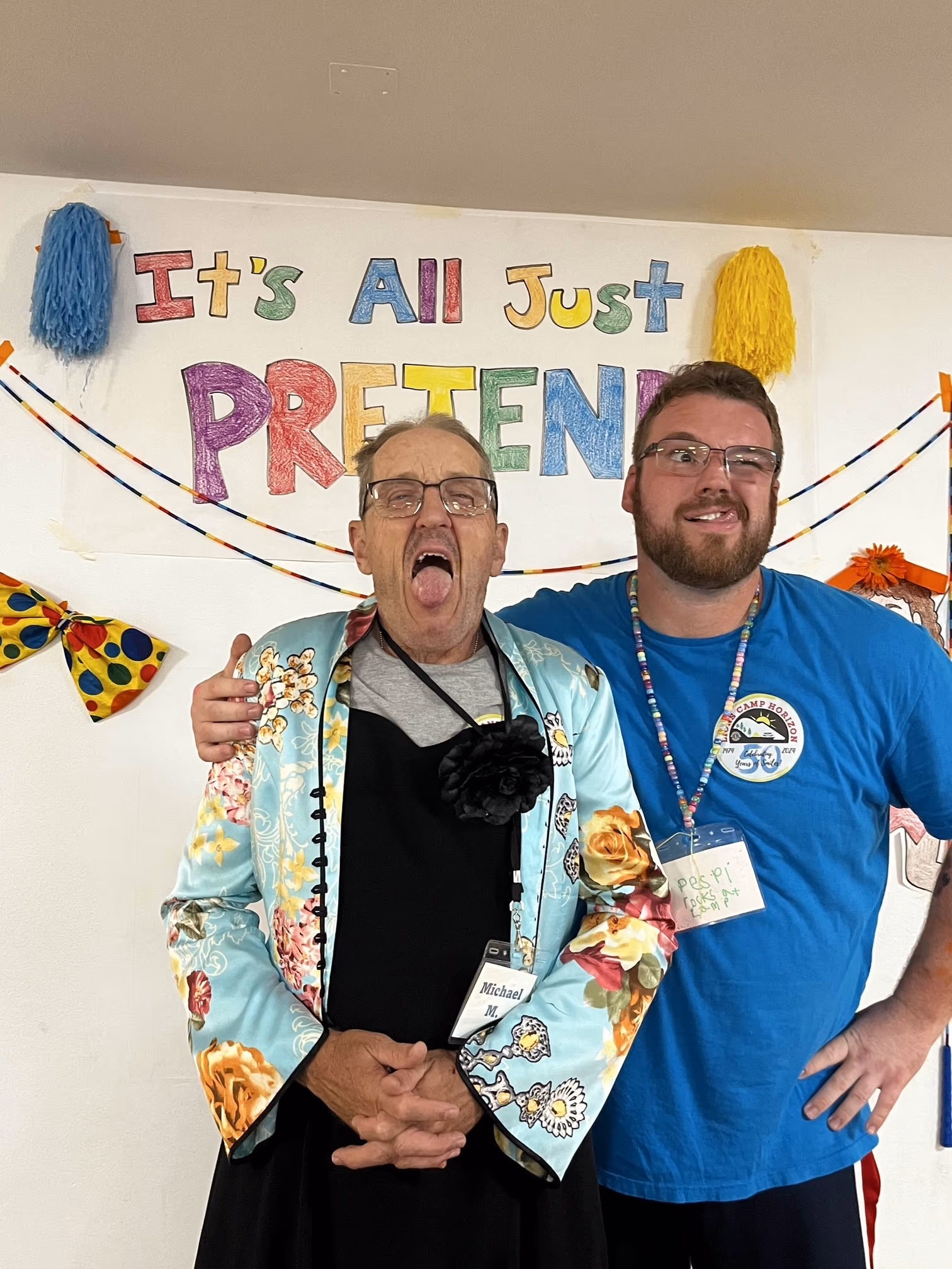 A camper and staff member with their tongues stuck out